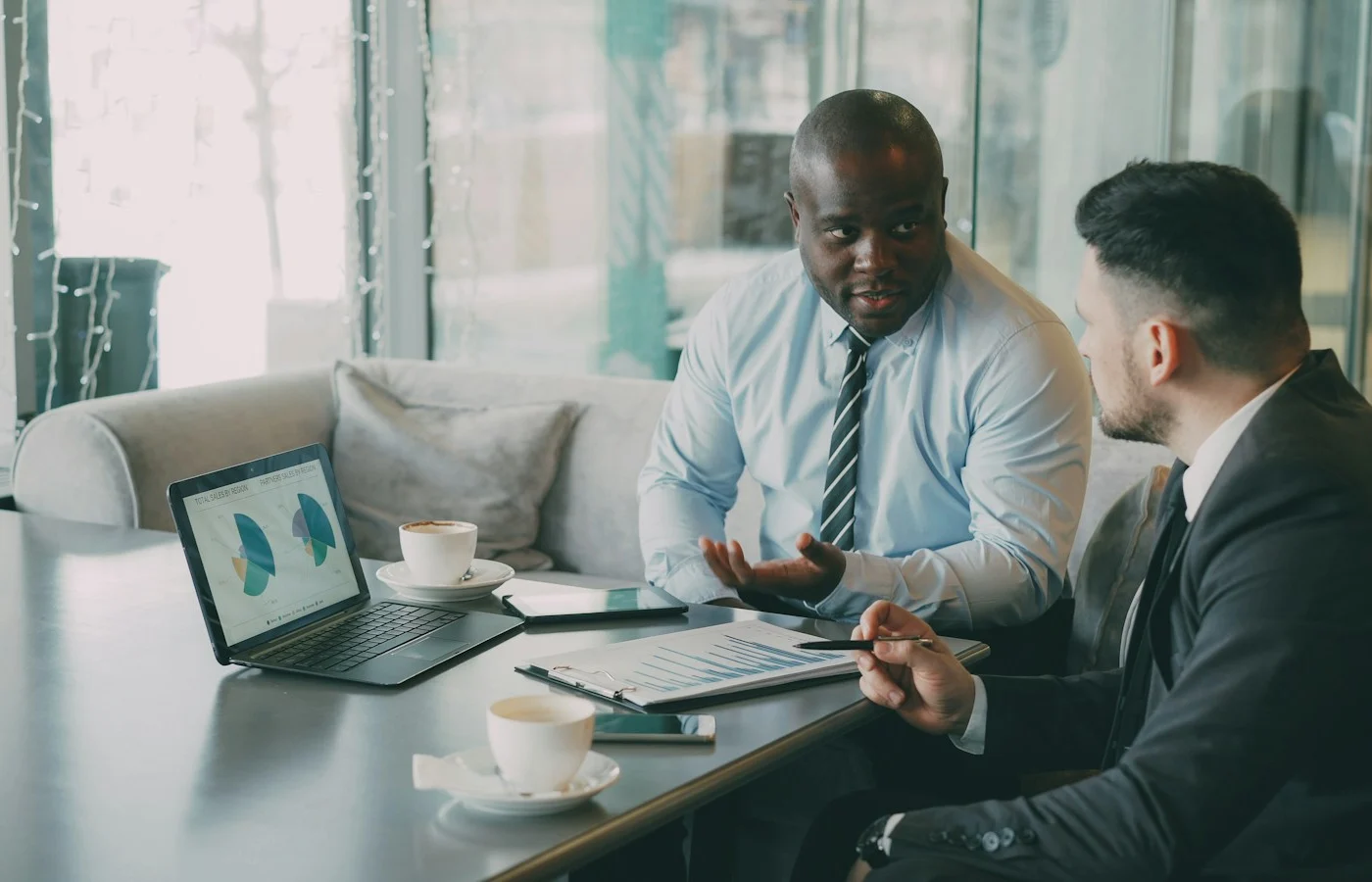 Two business people discussing charts on a laptop
